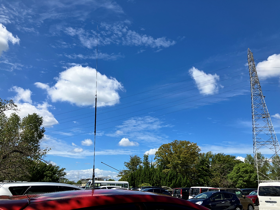 晴天で強い日差しのもと、木陰に停めて運用中のアンテナと車の写真