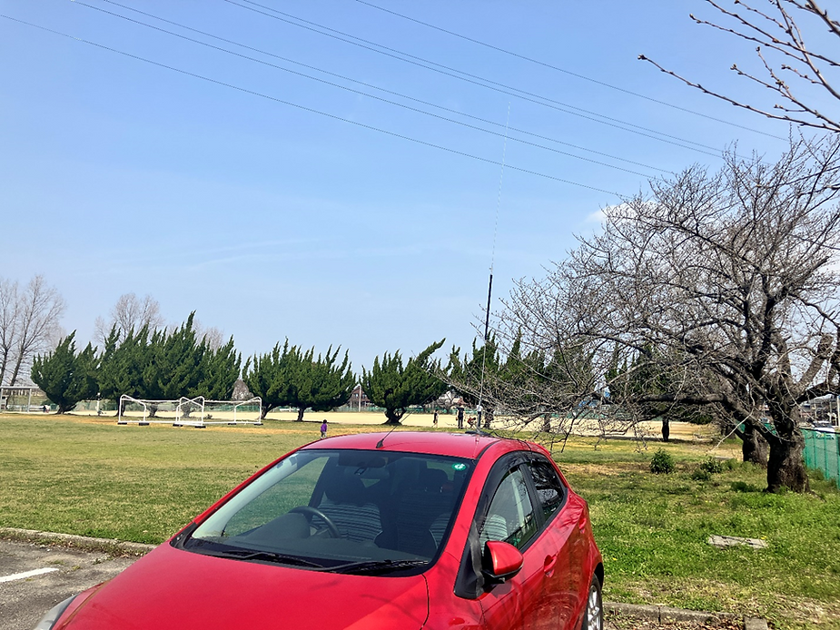 駐車場に停めた車とモービルホイップアンテナの写真